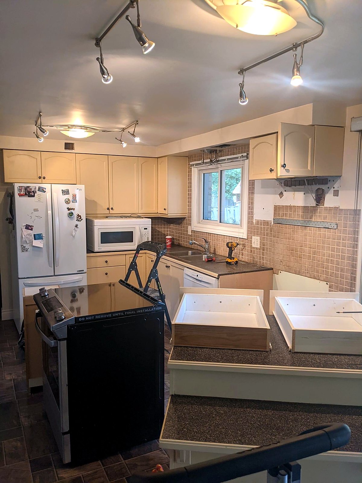 Kitchen before renovation — dated oak cabinets and track lighting